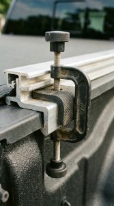 Close-up of a clamp-style mounting bracket on a truck bed rail.