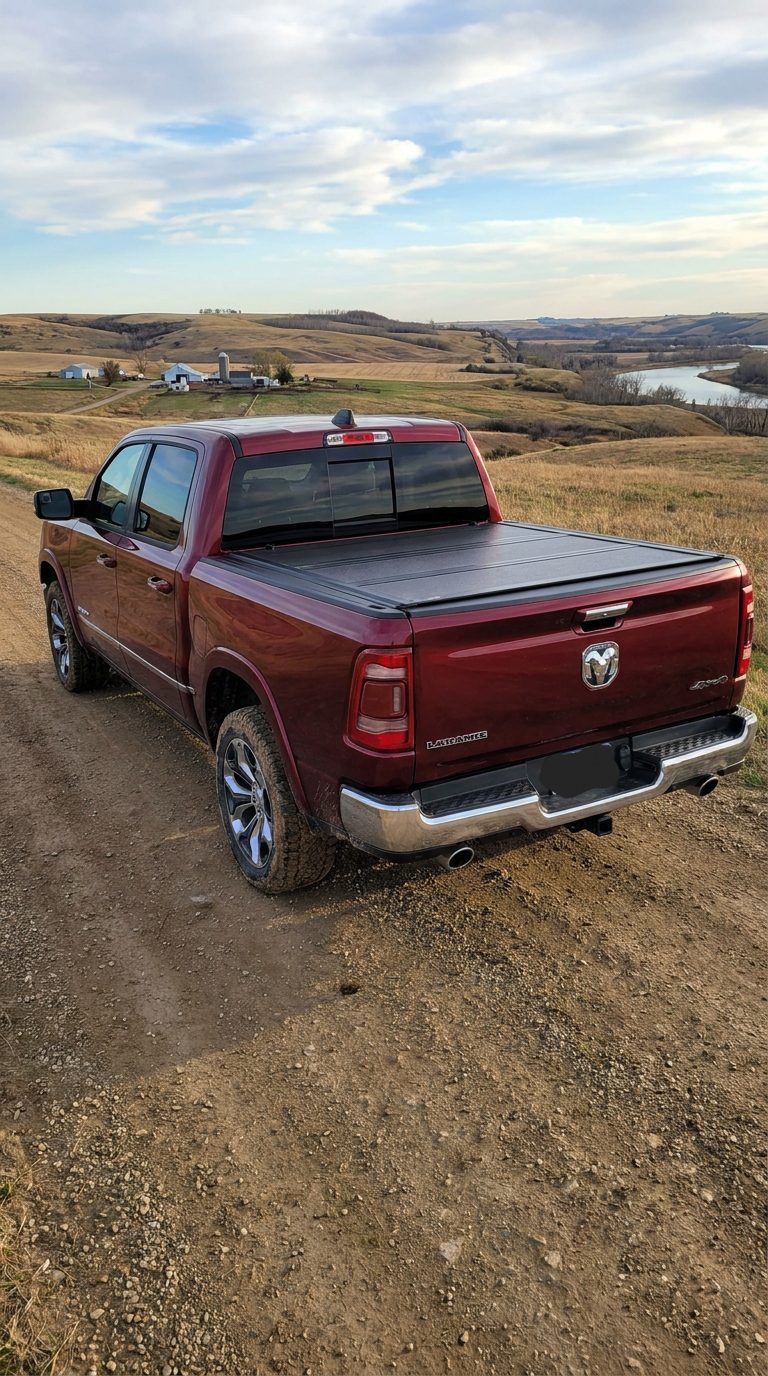 A Ram 1500 parked outdoors with a hard folding tonneau cover closed over the bed, shown from a rear three-quarter angle in daylight.